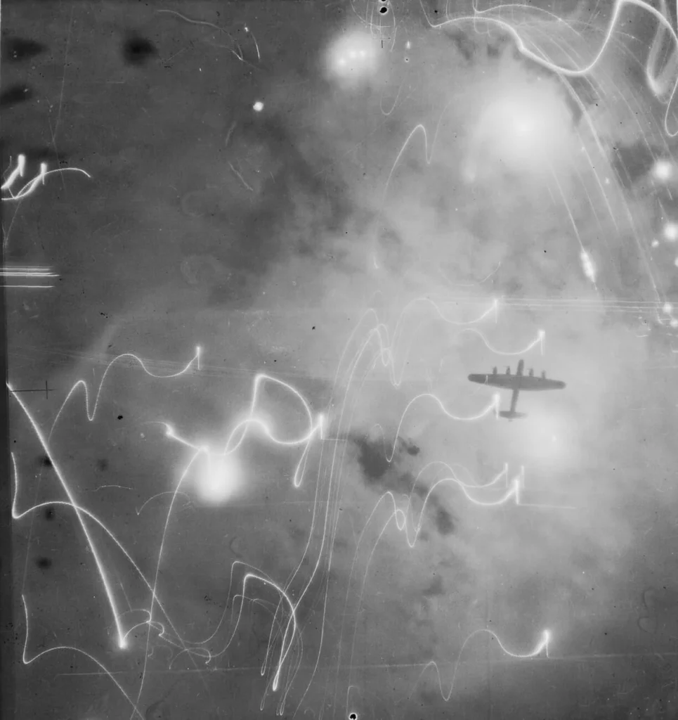 ハンブルク攻撃中の爆発と煙を背景に飛行するランカスター爆撃機