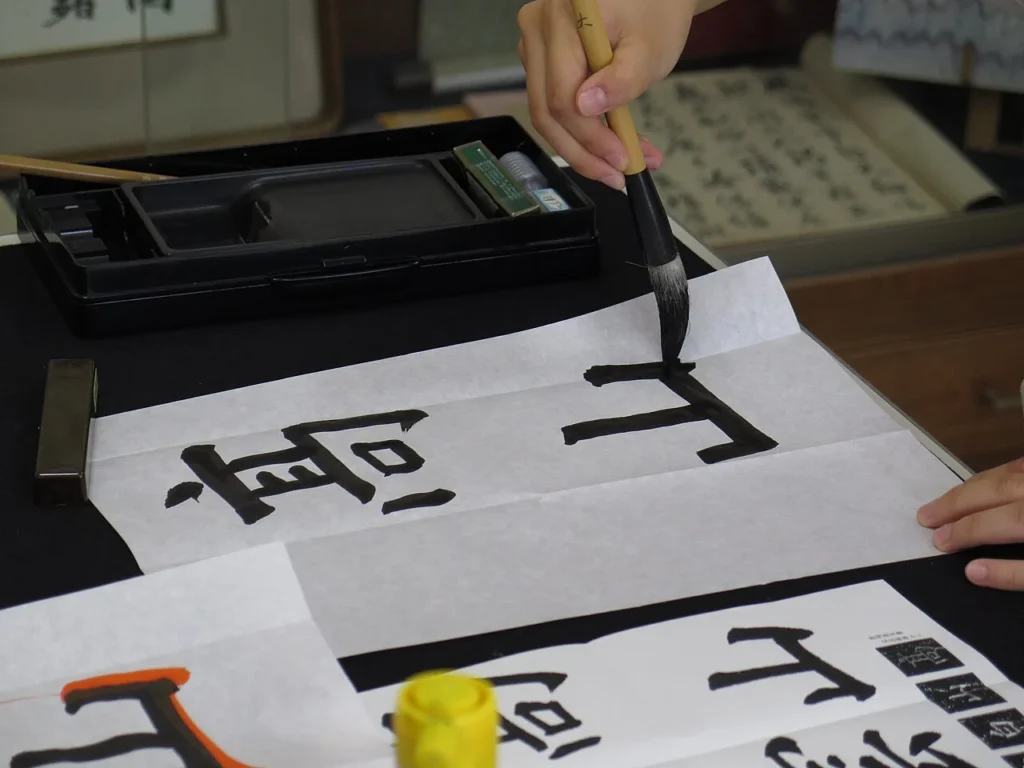 筆と墨で日本の書道に取り組む様子の写真