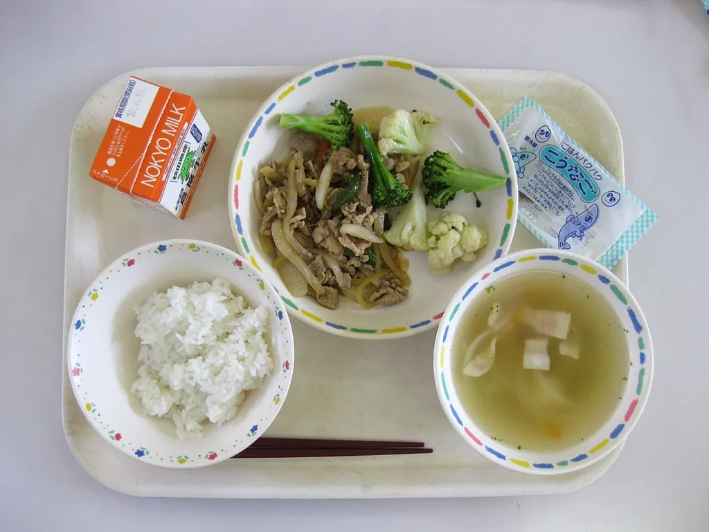 ご飯、みそ汁、牛乳、魚、豚肉と野菜の料理を組み合わせた日本の学校給食