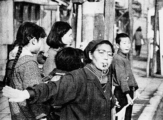 通学する児童を見守る緑色の制服姿の学童擁護員
