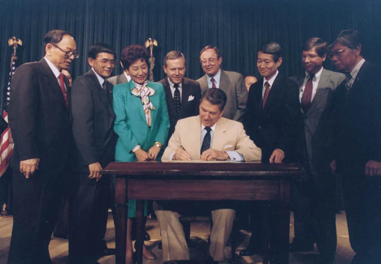 レーガン大統領が1988年の市民の自由法に署名する写真